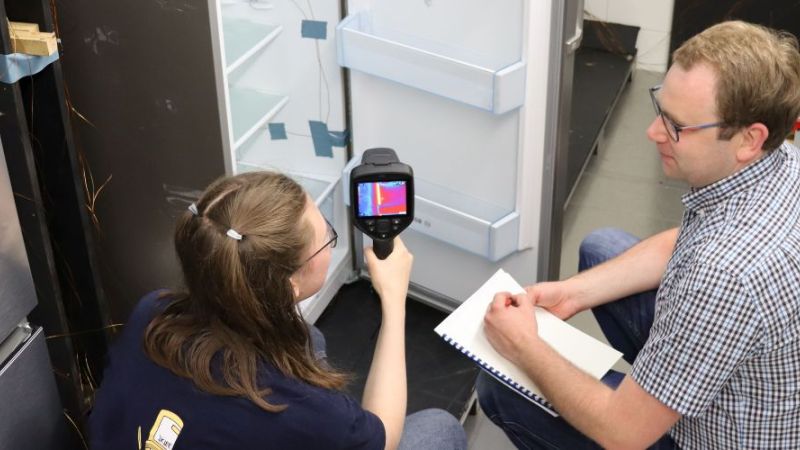 WissenschaftlerInnen untersuchen mit einem Messgerät einen Kühlschrank