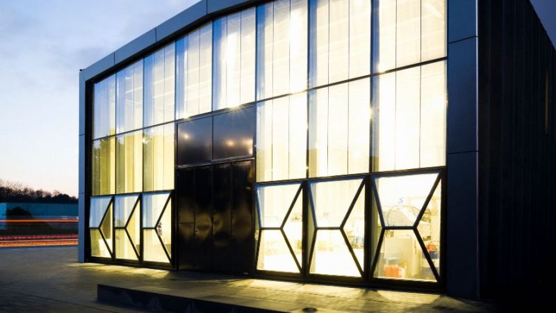 Eine Fabrik ist von der Seite zu sehen. EIne Fassade besteht konplett aus Glas.