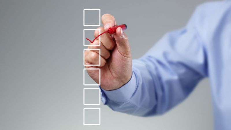 Nahaufnahme einer Hand, die eine Checkliste abhakt
