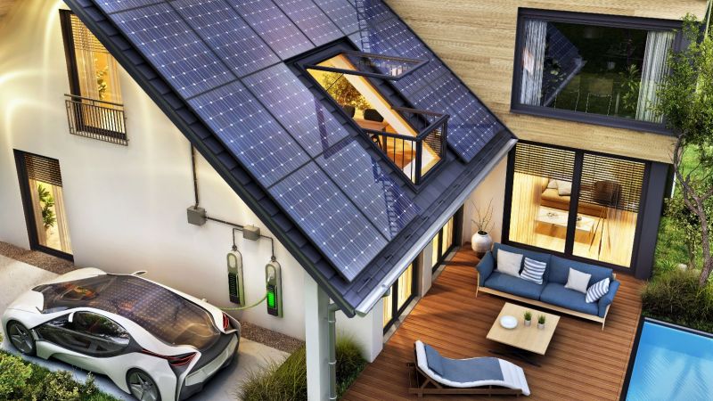 ein parkendes Elektro-Auto lädt im Carport eines modernen Einfamilienhauses mit Solardach
