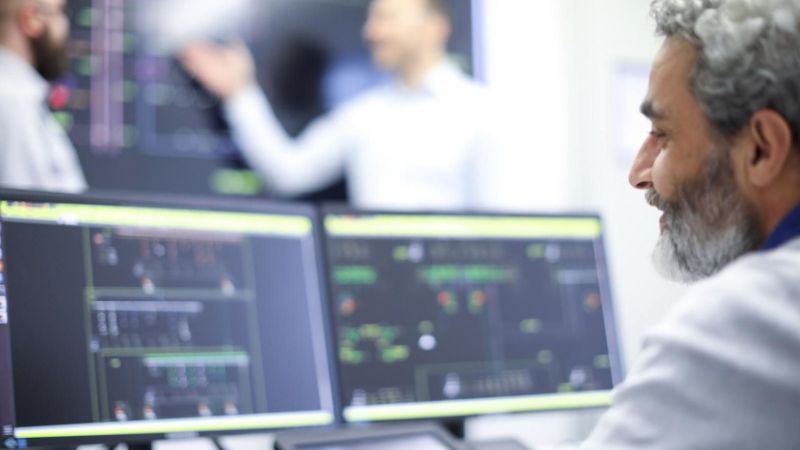 Projektmitarbeiter sitzt am Rechner und bearbeitet einen Plan zum Netzbetrieb von Stromnetzen.
