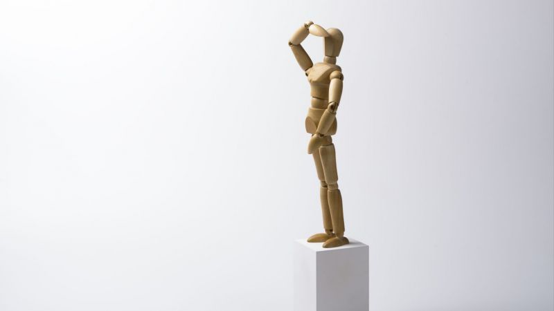 Holzfigur steht auf Sockel und schaut in die Ferne
