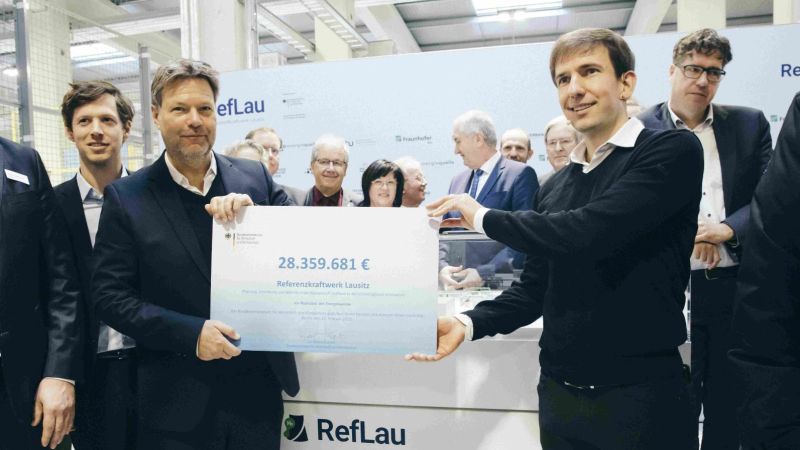Der Minister überreicht den symbolischen Förderbescheid für das Vorhaben RefLau an den Projektleiter.