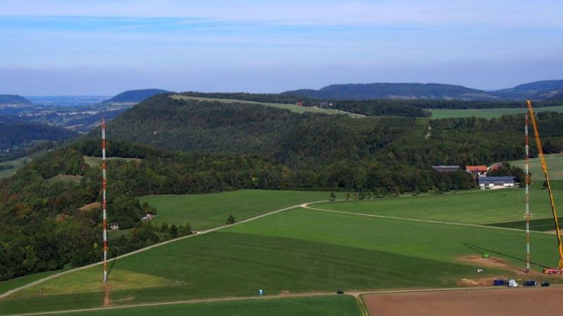 Errichtung der bereits stehenden Messmasten für das Windenergietestfeld in bergigem Gelände.