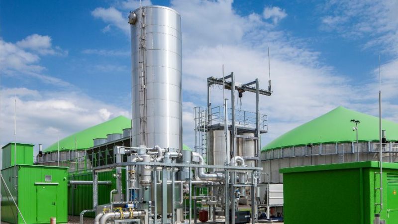 Das Foto zeigt eine Gasaufbereitungsanlage einer Biogasanlage, im Hintergrund sind Fermenter zu sehen.