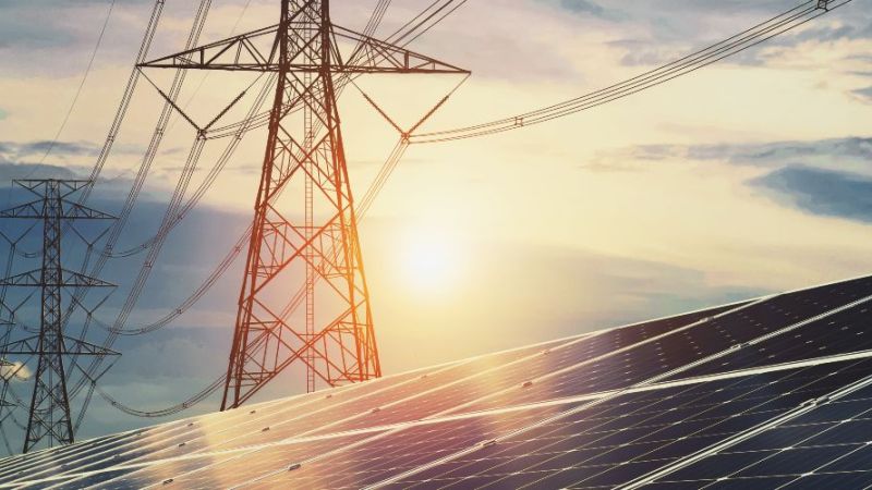 The photo shows an industrial photovoltaic system with high-voltage transmission lines in the background.