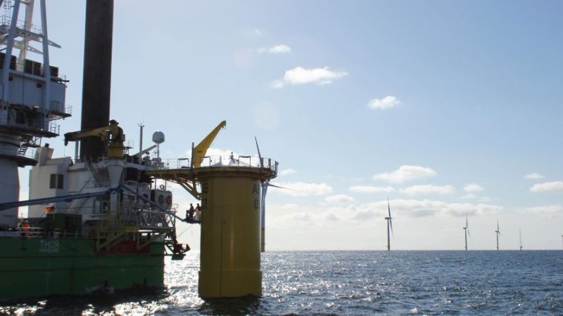 Auf dem Meer wird eine Offshore-Windenergieanlage aufgebaut.