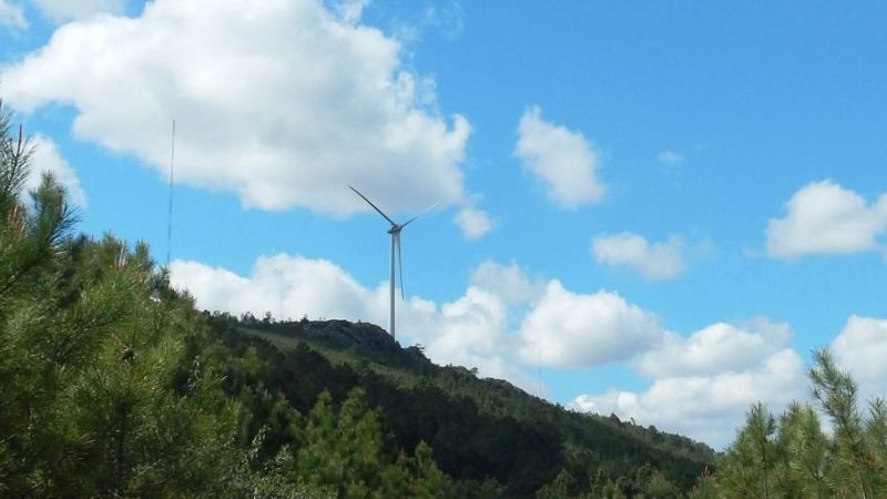 The photo shows an ENERCON wind turbine on a hill.
