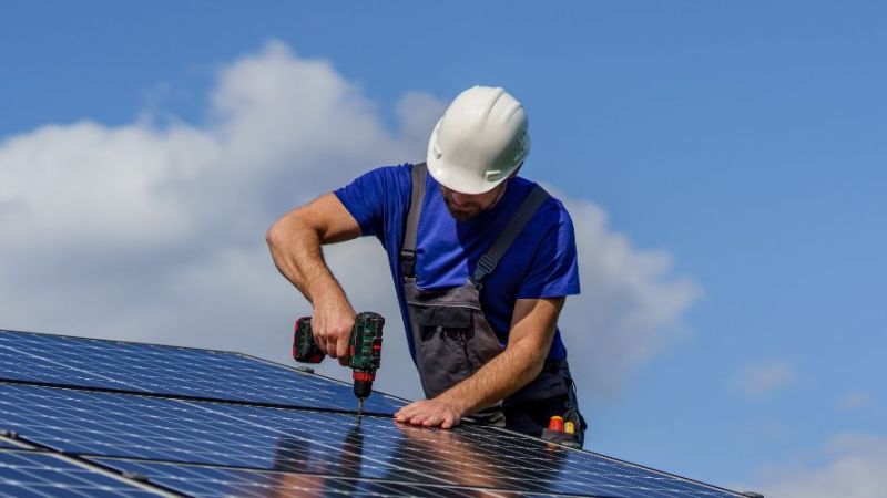 Symbolfoto: Arbeiter bei der Installation von Solarzellen auf einem Dach.