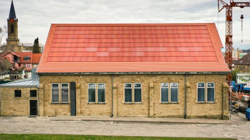 Das Foto zeigt die ziegelrote Photovoltaikanlage auf dem Dach einer Turnhalle in Eppingen, die im Rahmen des Forschungsprojekts PVHide entwickelt wurde.