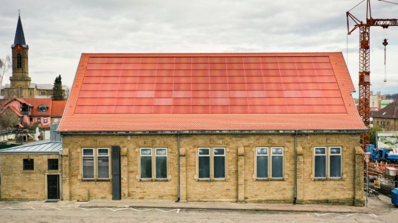 The photo shows the brick-red photovoltaic system on the roof of a gymnasium in Eppingen, which was developed as part of the PVHide research project.