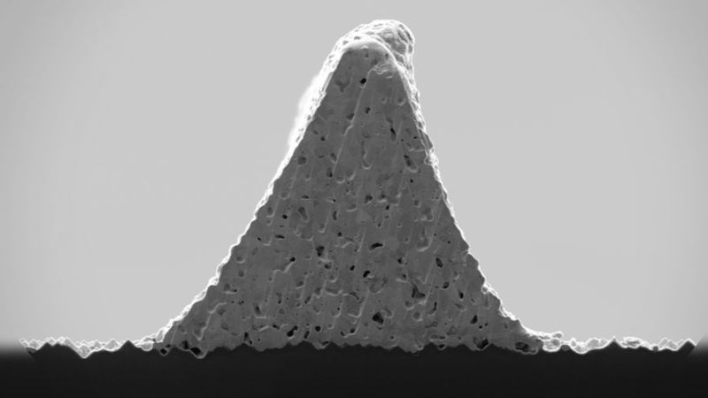 Rasterelektronenmikroskop-Aufnahme: Ein dreieckiger Solarzellenkontakt mit glatten Außenkanten ist im Querschnitt zu erkennen. Dieser befindet sich auf einer Solarzelle.
