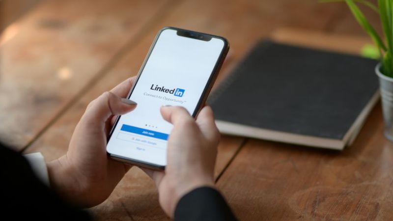 Eine Frau ruft den Kanal der Energieforschung bei LinkedIn mit ihrem Smartphone auf. 