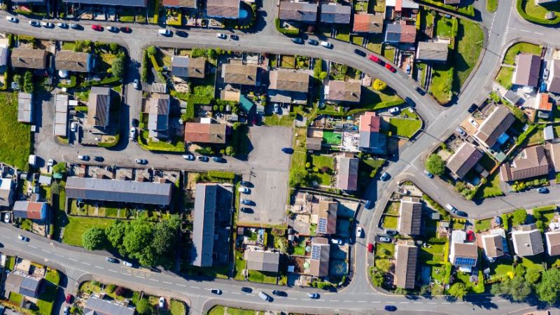 Luftaufnahme einer Drohne von kleinen kurvigen Straßen und Wegen in einem Wohngebiet einer Kleinstadt.