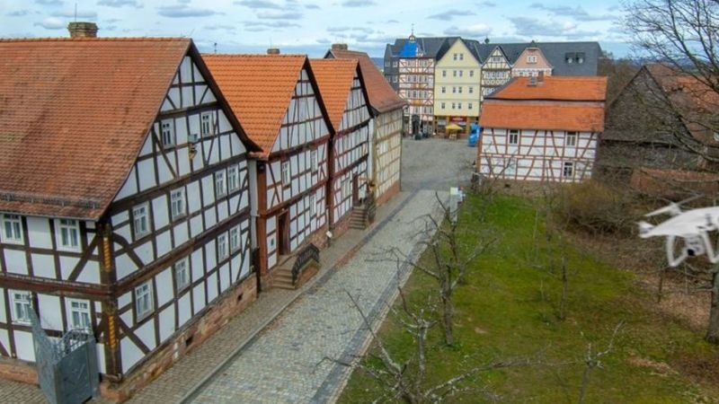 Hier werden die drei Versuchsgebäude mit Hilfe einer Drohne geometrisch erfasst. Bauwerksaufnahme mithilfe einer Drohne.