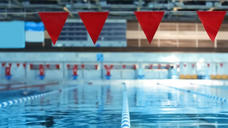 Ein Schwimmbecken mit mehreren Bahnen und roten Fahnen am oberen Bildrand.