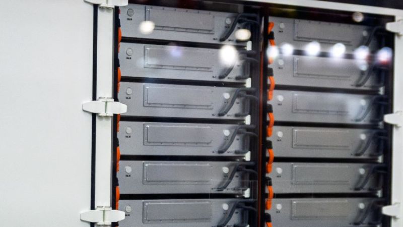 Ausschnitt eines Batterieschranks, eine Tür ist geöffnet und gibt den Blick frei auf die silbernen, rechteckigen Batterieelemente.