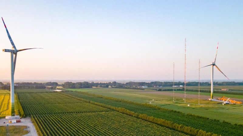 Luftaufnahme von landwirtschaftlichen Feldern mit zwei Windkraftanlagen bei Sonnenuntergang