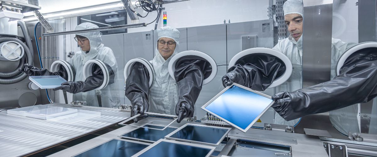 Wissenschaftlerinnen und Wissenschaftler an einer Verdampfer-Anlage mit gro&szlig;en Silizium-Wafern. Das Pero-Si-SCALE &uuml;berf&uuml;hrt die Zelldesigns aus dem Labor auf industrielle Zellformate.