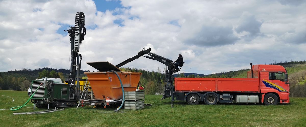Testbohrung mit Bohrgerät und LKW auf einer Wiese.