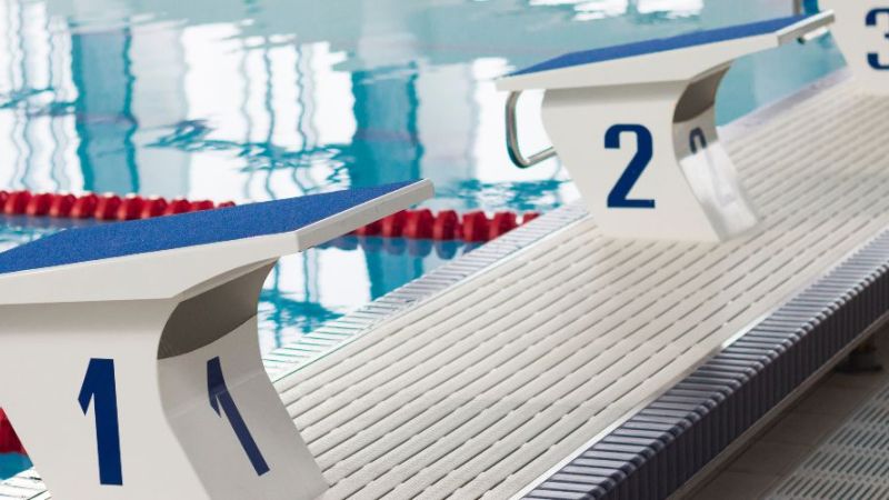 Ein Schwimmbecken mit mehreren Bahnen und roten Fahnen am oberen Bildrand.
