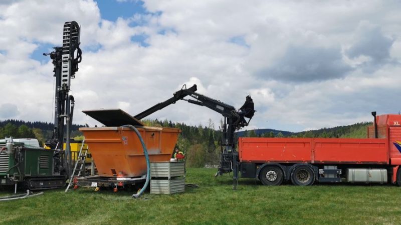 Testbohrung mit Bohrgerät und LKW auf einer Wiese.