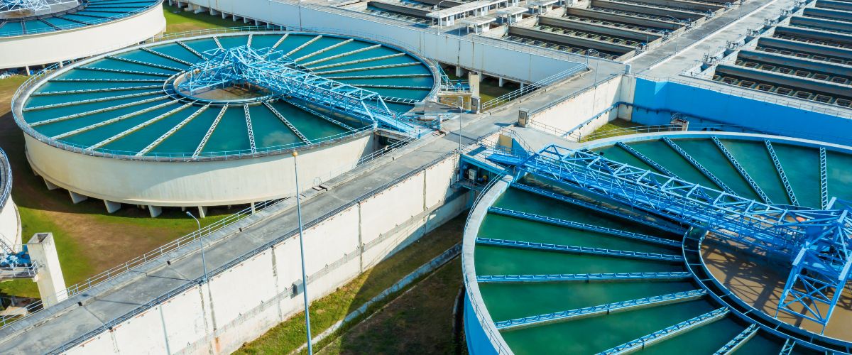 Luftaufnahme einer Trinkwasseraufbereitungsanlage mit mehreren runden und rechteckigen Wasserbecken sowie technischen Anlagen zur Wasseraufbereitung.