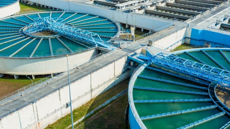 Luftaufnahme einer Trinkwasseraufbereitungsanlage mit mehreren runden und rechteckigen Wasserbecken sowie technischen Anlagen zur Wasseraufbereitung.