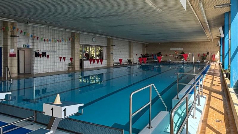 Ein Schwimmbecken mit mehreren Bahnen und roten Fahnen am oberen Bildrand.