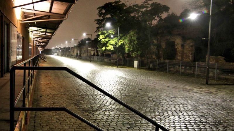 Efficiently illuminating paths and squares with LEDs: A section of the loading road can be seen, which is equipped with masts, each of which is fitted with three luminaires at different heights.