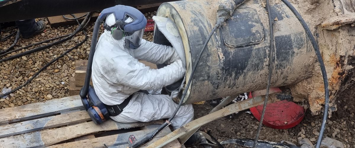 Arbeiter schneidet einen ausgehärteten Carbonfaser-Liner zurecht.