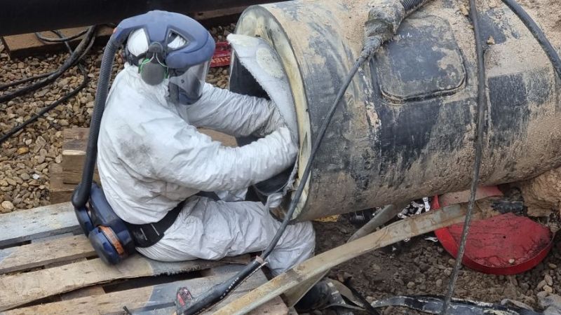 Arbeiter schneidet einen ausgehärteten Carbonfaser-Liner zurecht.