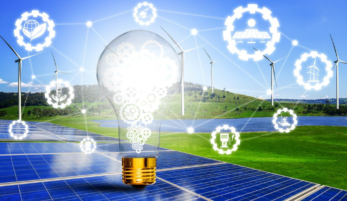 Symbolbild für das Energiesystem mit einer Glühbirne mit Zahnrädern vor Windrädern und einer Solaranlage, umrandet von Kugeln mit Energiesymbolen