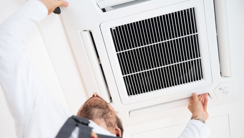 Lüftungsanlagen sind insbesondere während der Corona-Pandemie mehr in Fokus gerückt. Ein Monteur arbeitet an einer Lüftungs-/Klimaanlage.