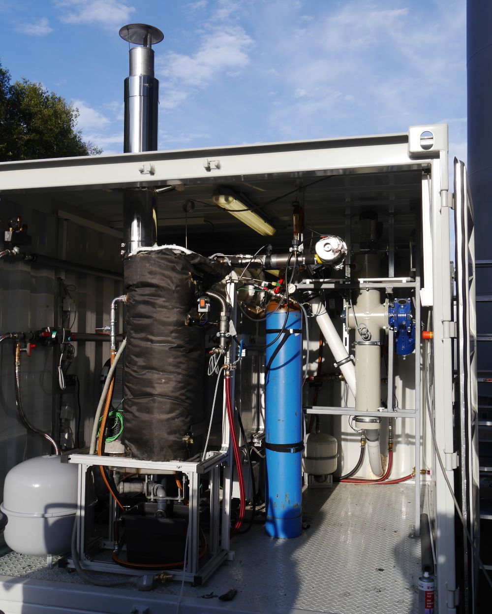 The photo shows the developed MINI CHP system with Stirling engine in a steel shell in a mobile container. 