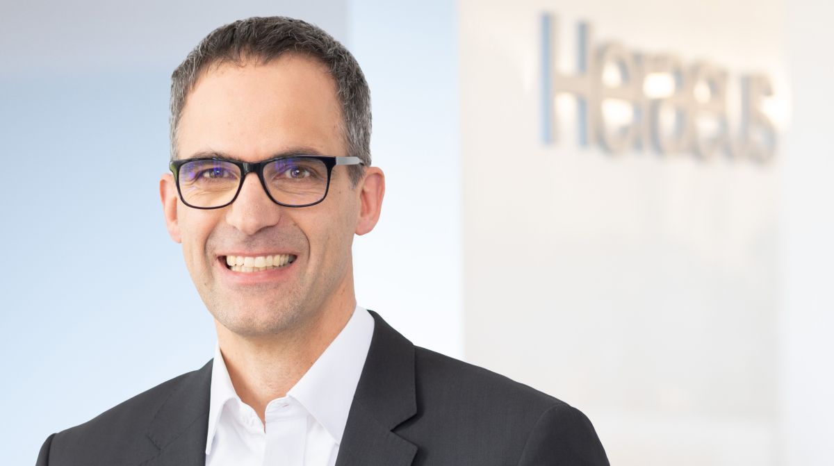Porträtbild von Dr. Wilfried Lövenich vor dem Firmenlogo Heraeus