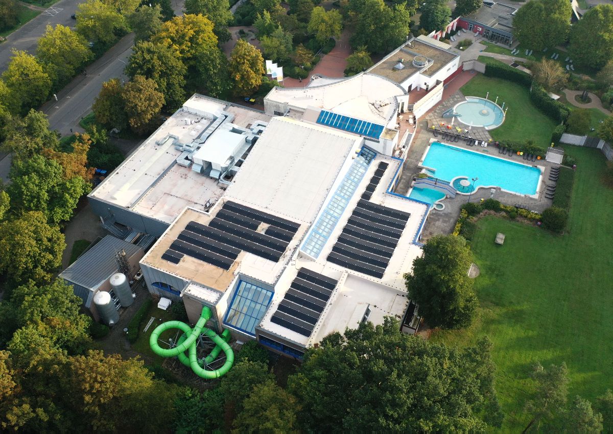 Luftaufnahme des Aquarius Freizeitbads in Borken mit Hallenbad, Außenbecken, Grünflächen und Photovoltaikanlagen auf den Dächern.