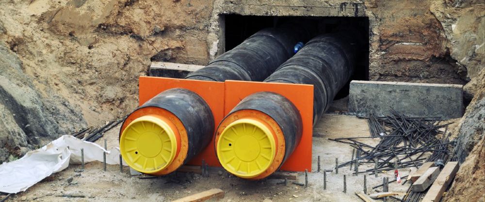 Zwei gedämmte Fernwärmeleitungen werden auf einer Baustelle unterirdisch verlegt.